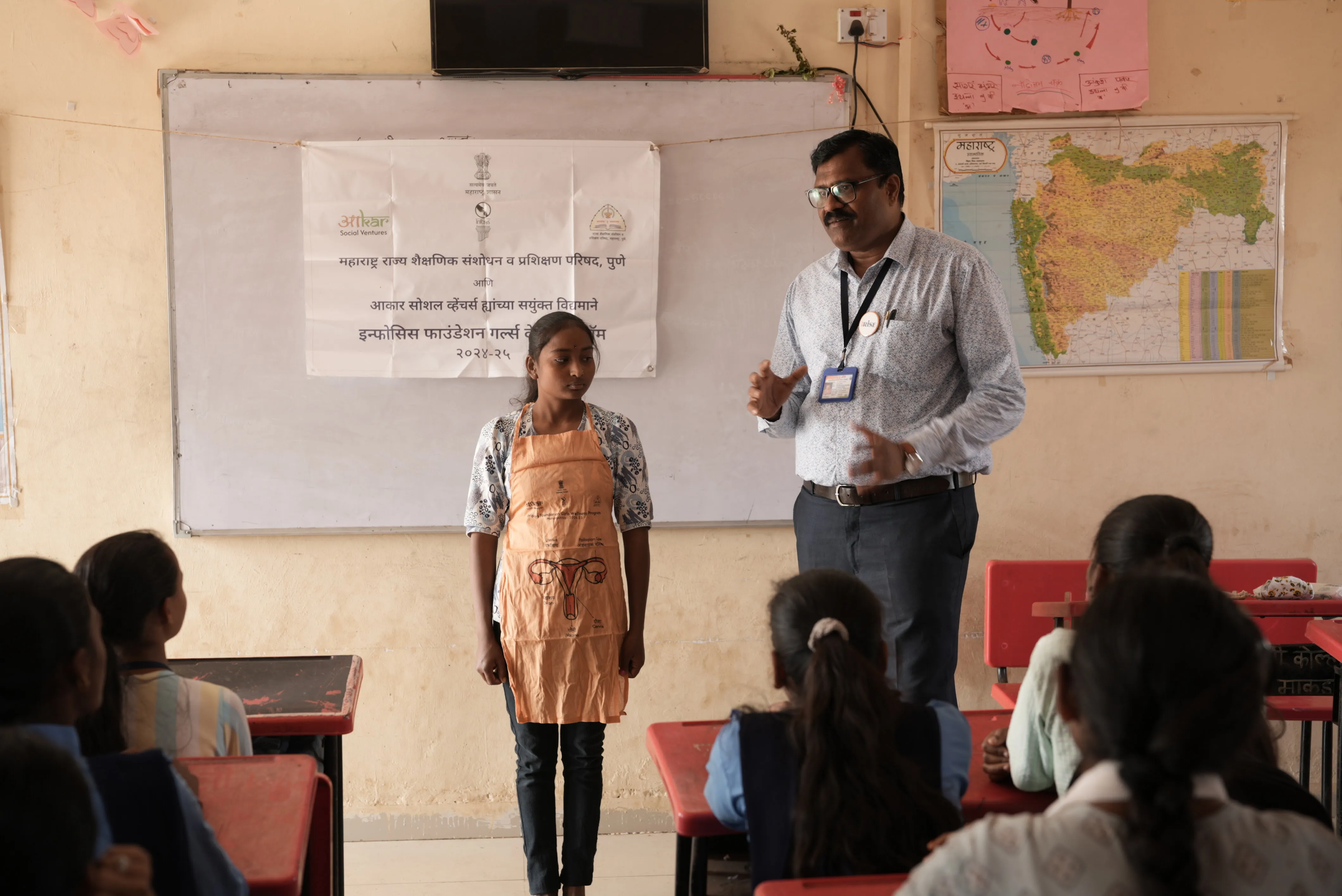 Nitin More explaining the reproductive system using an anatomy apron in a classroom - Aakar Social Ventures Field Story